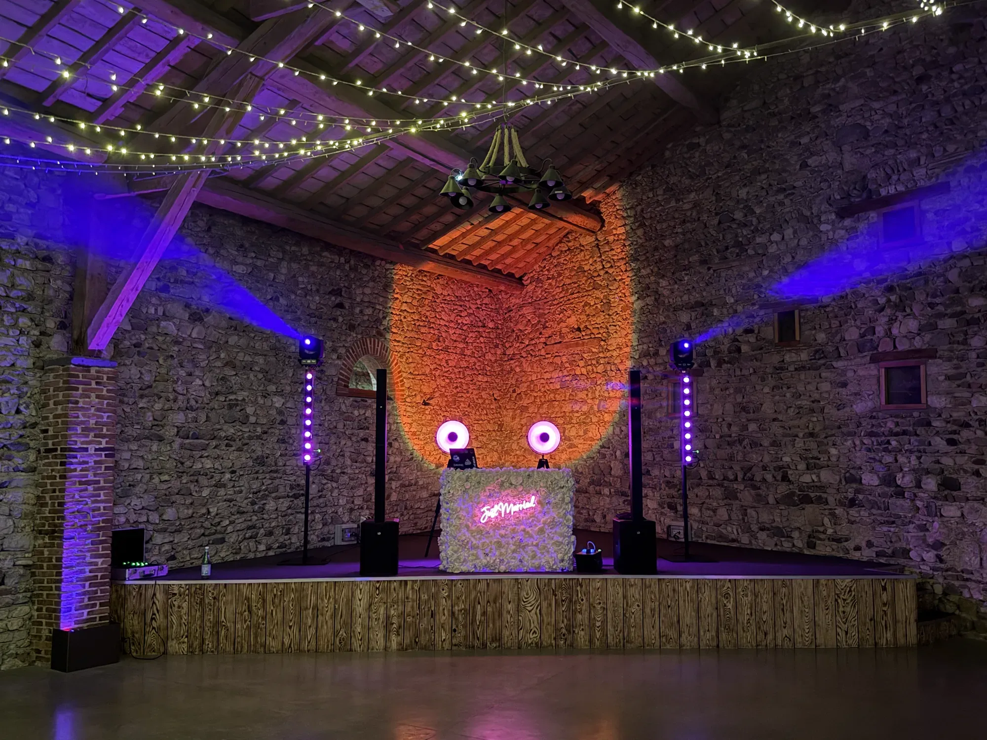 Installation DJ au Château de Gondole, au Cendre : le stand habillé de fleurs blanches, avec son néon « Just married »