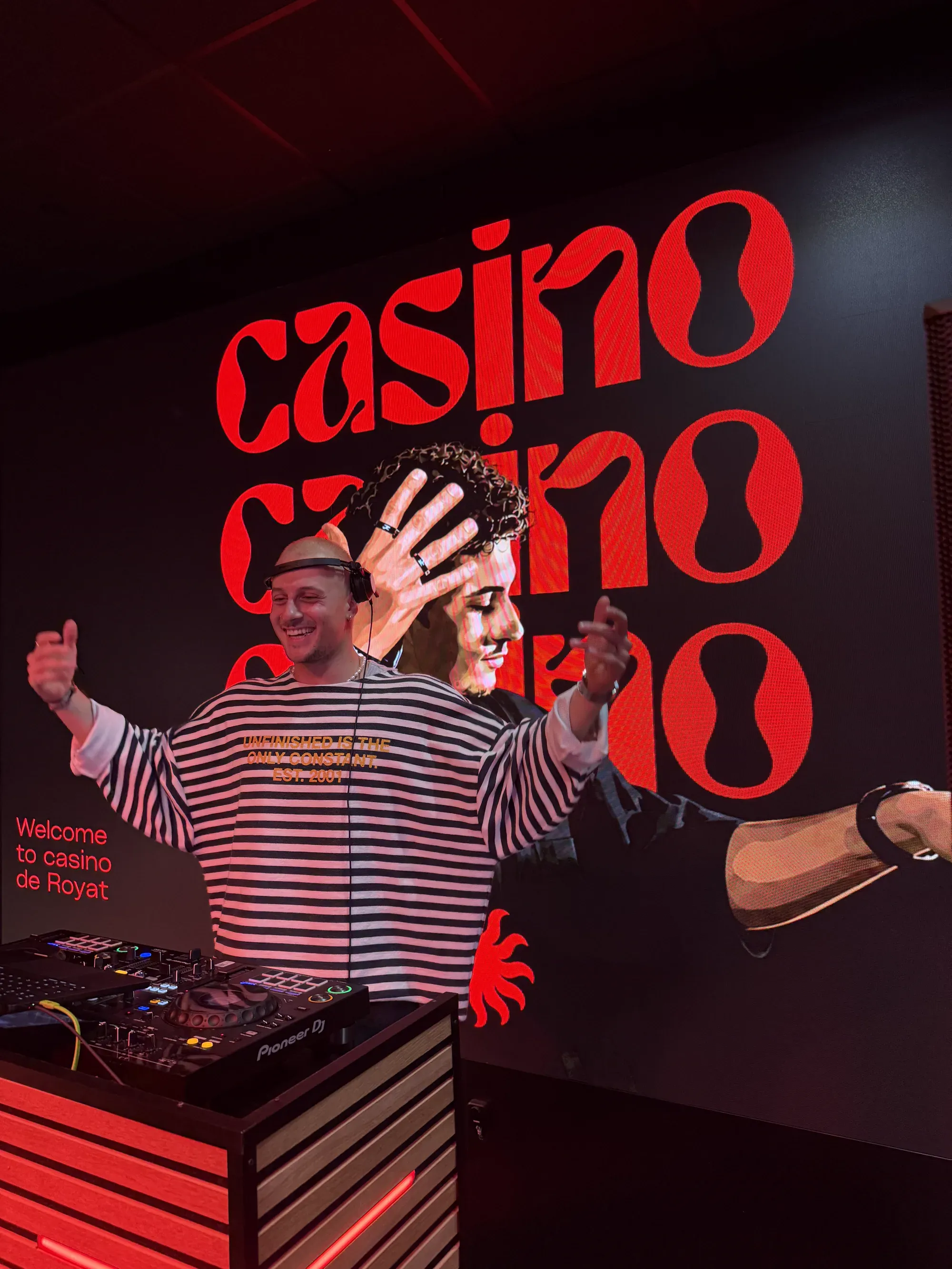 Léo Caussanel, DJ, riant les bras écartés derrière son contrôleur, devant un grand écran rouge affichant « casino » et « Welcome to casino de Royat »