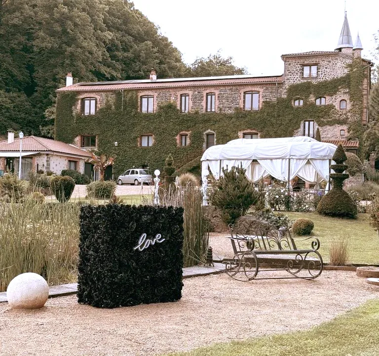 Le stand habillé de fleurs noires, avec son néon « love », sur le gravier, devant un château couvert de lierre