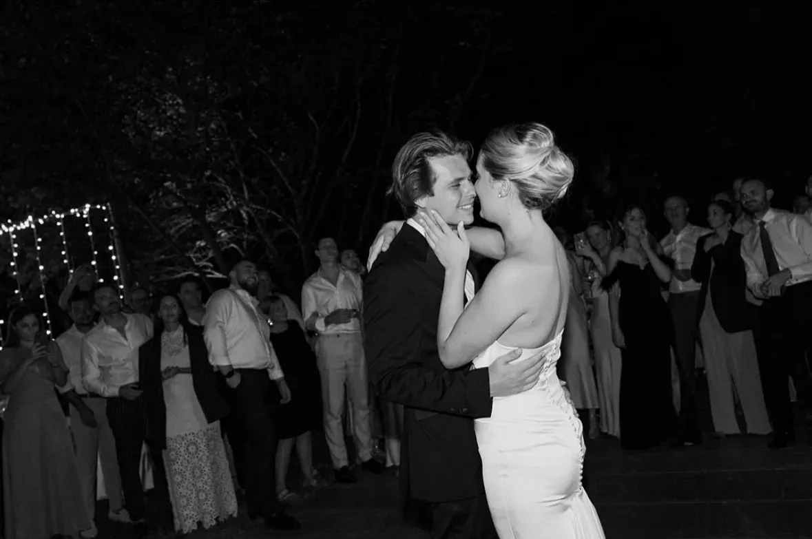 Les mariés dansent enlacés au milieu de la piste, sous le regard des invités. Photo en noir et blanc.